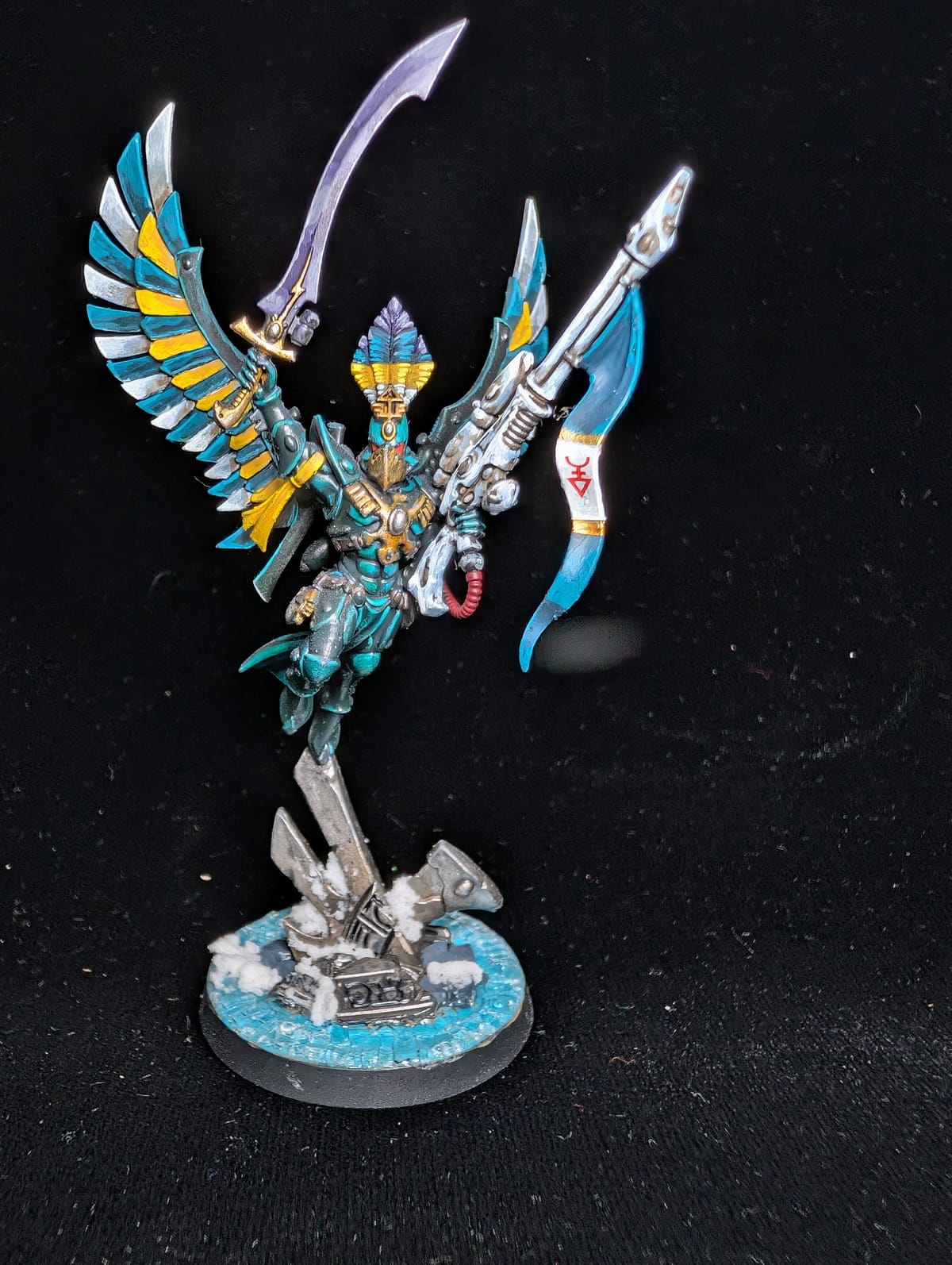 Aeldari Phoenix Lord Baharroth in turquoise and white armour with gold wings, leaping above an ice base