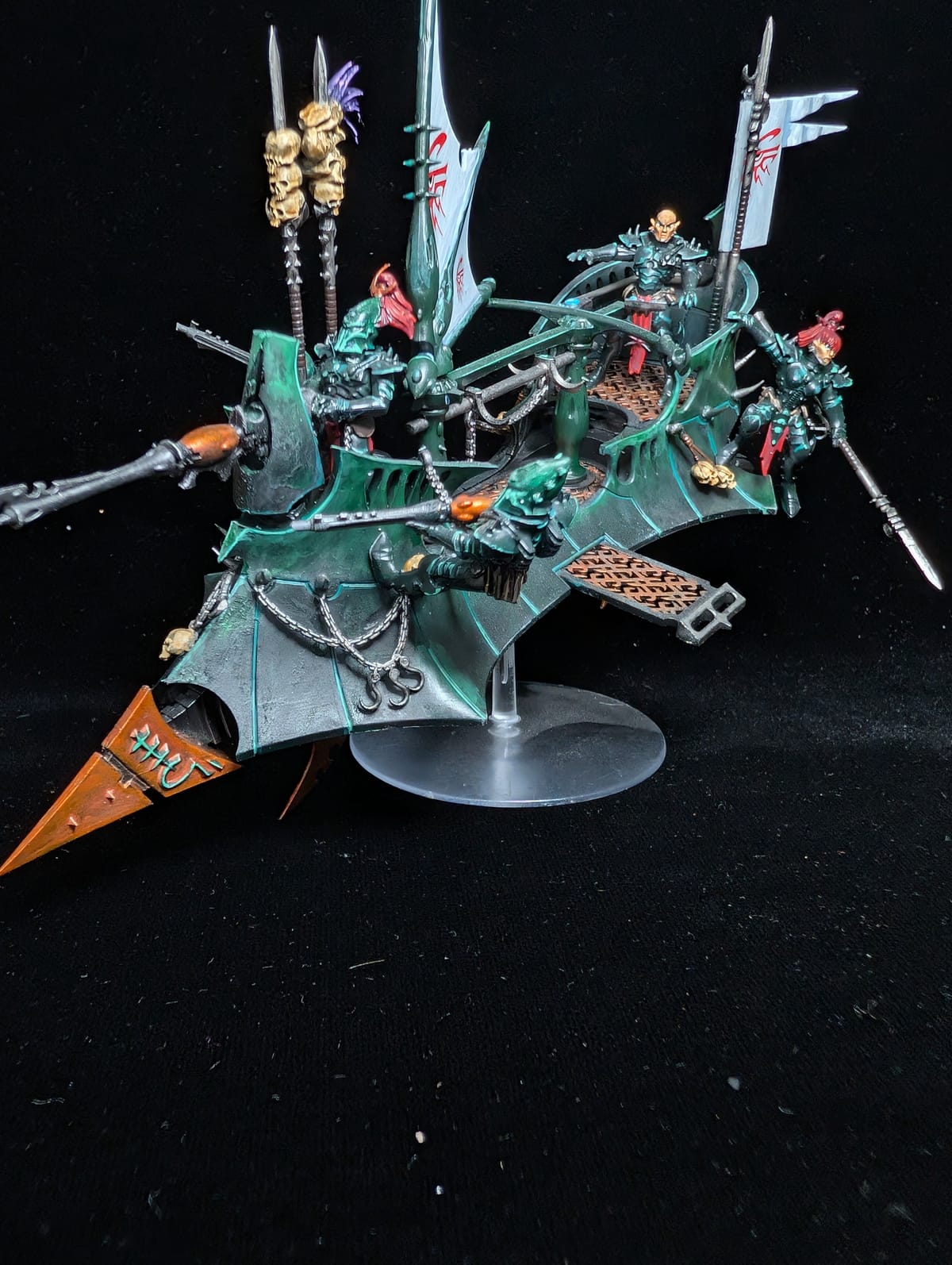 Drukhari Raider skimmer in teal with red sails and blades, on a flying stand